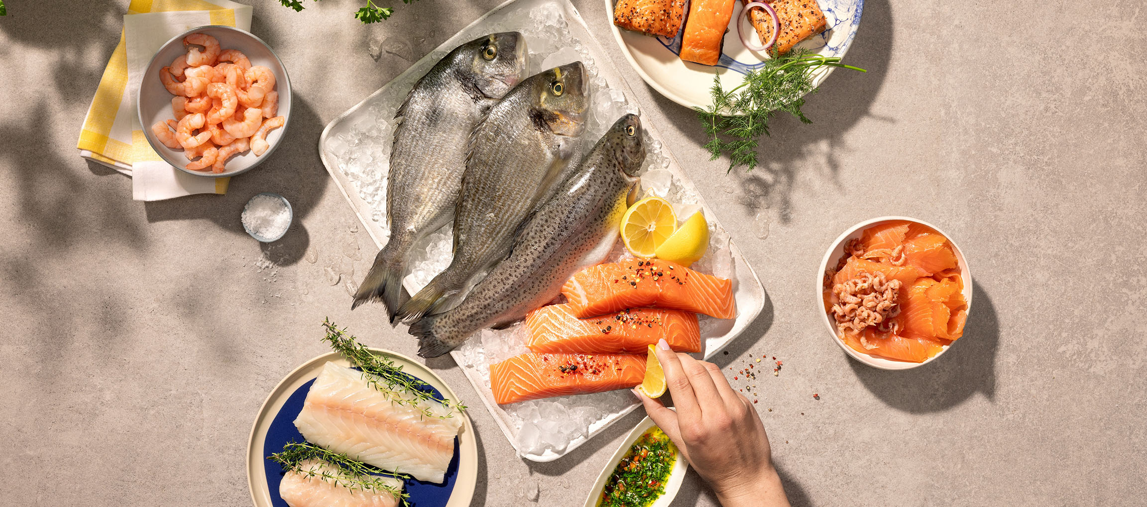 Assortment of fresh seafood, including whole fish, salmon fillets, and shrimp, on ice.