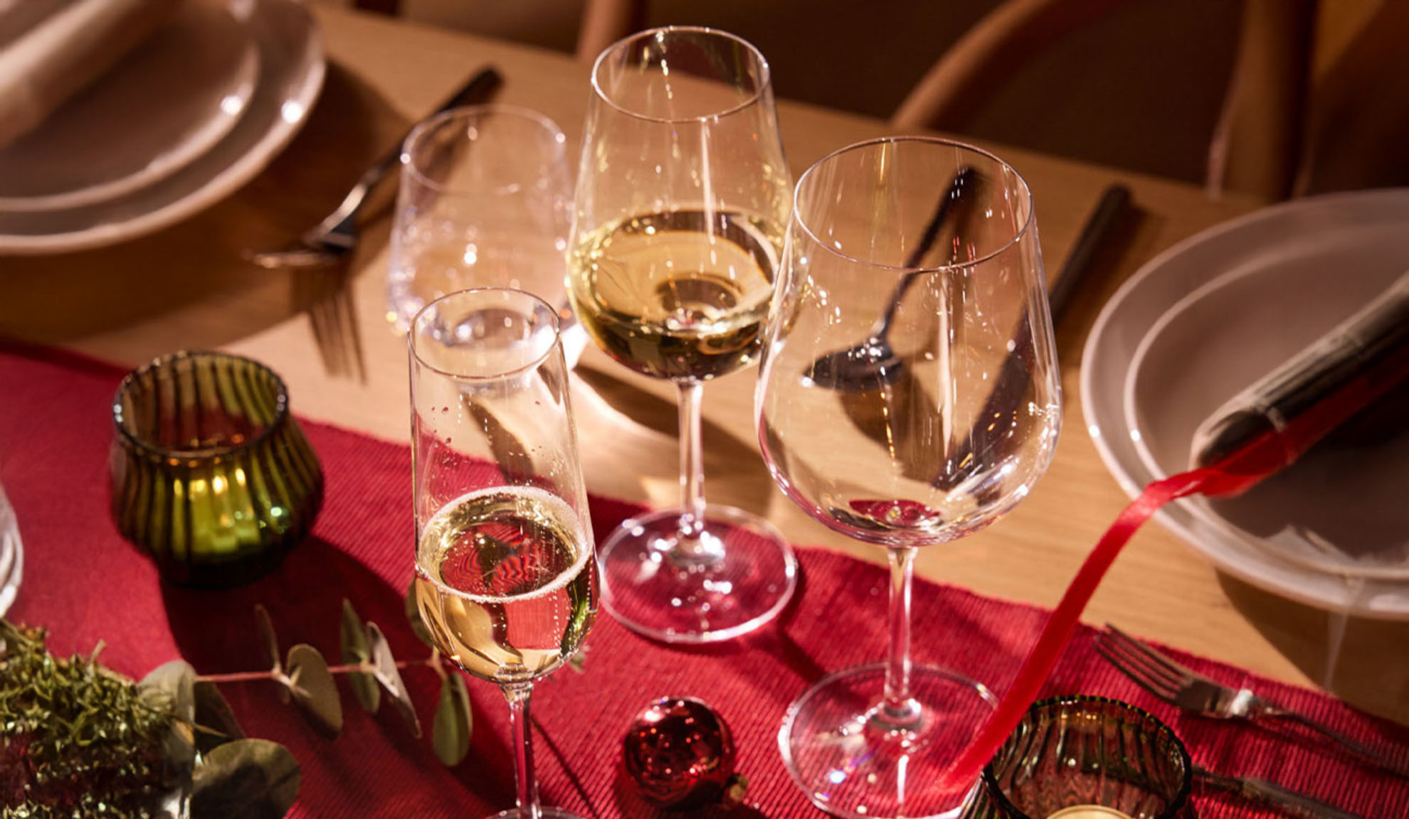 Γιορτινό τραπέζι στρωμένο με ποτήρια κρασιού, ποτήρι σαμπάνιας και χριστουγεννιάτικα στολίδια.