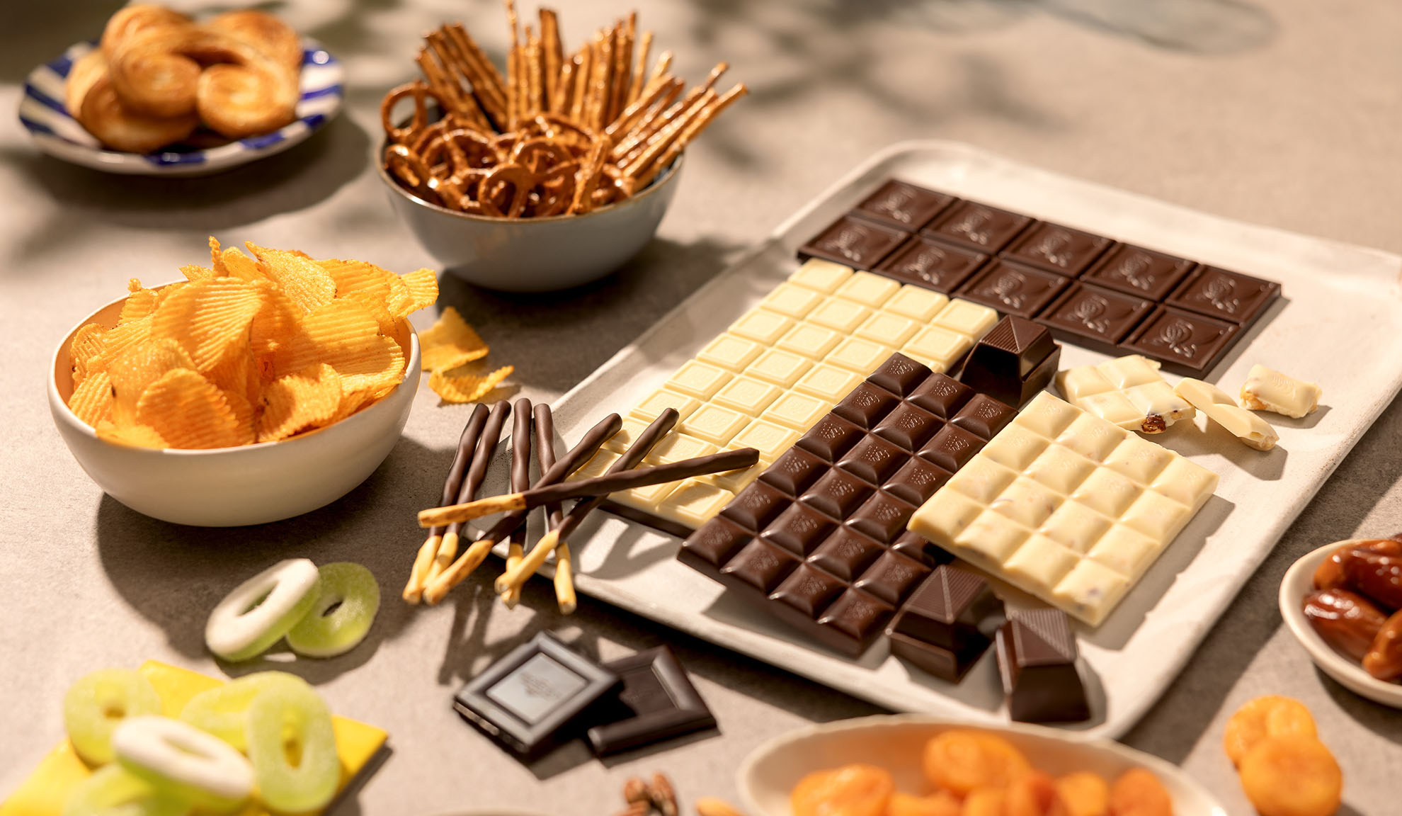 An assortment of snacks including chocolate bars, potato chips, pretzels, and sweets.