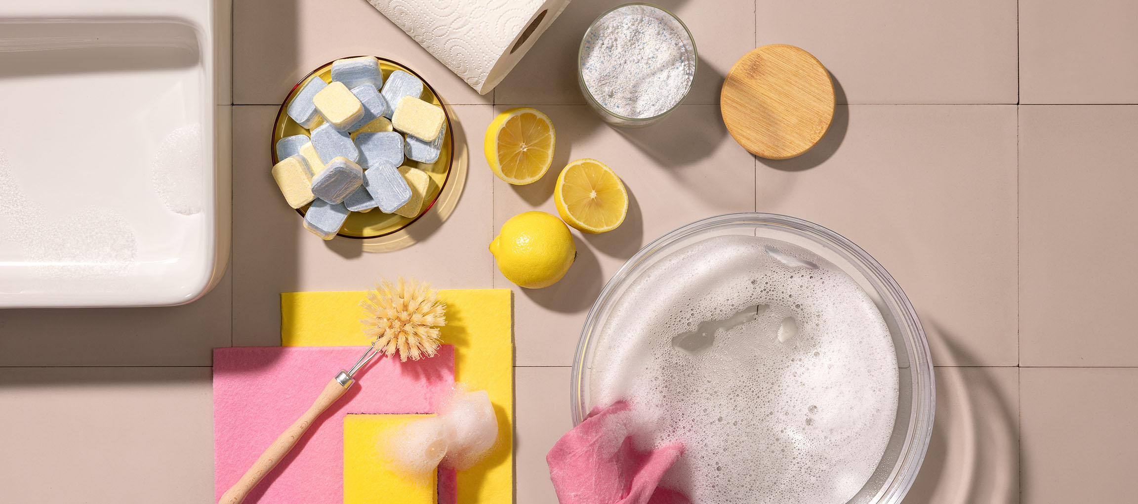 Cleaning supplies: dishwasher tablets, lemons, powder, brush, and cloths.