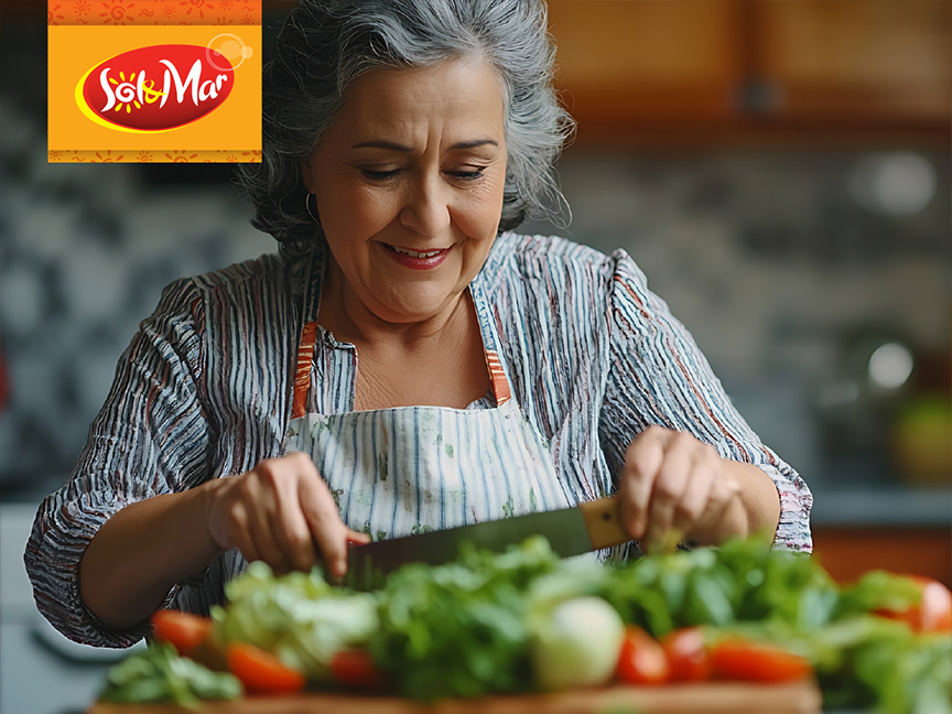 A smiling woman prepares a salad, using Sol y Mar products in her kitchen.