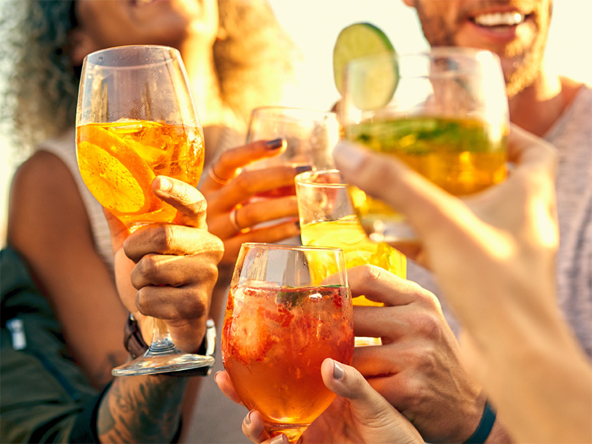 Φίλοι συγκρούουν ποτήρια με Aperol spritz και άλλα καλοκαιρινά κοκτέιλ.
