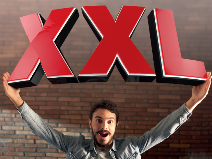 Ένας άντρας κρατάει μεγάλα γράμματα XXL, παρουσιάζοντας εξαιρετικά μεγάλα μεγέθη.