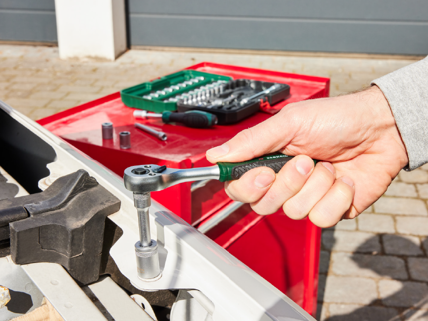 A person uses a Parkside ratchet to tighten a bolt on a vehicle.