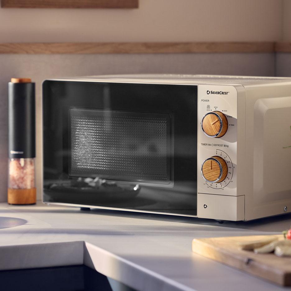 Cream microwave with wooden knobs on a kitchen counter.