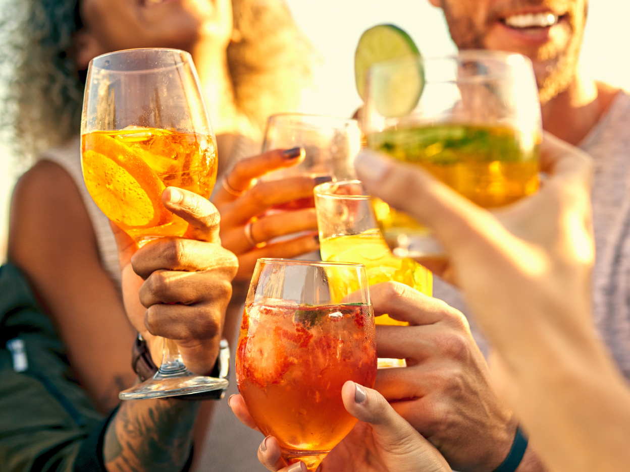 Friends celebrate with cocktails at a sunny party.
