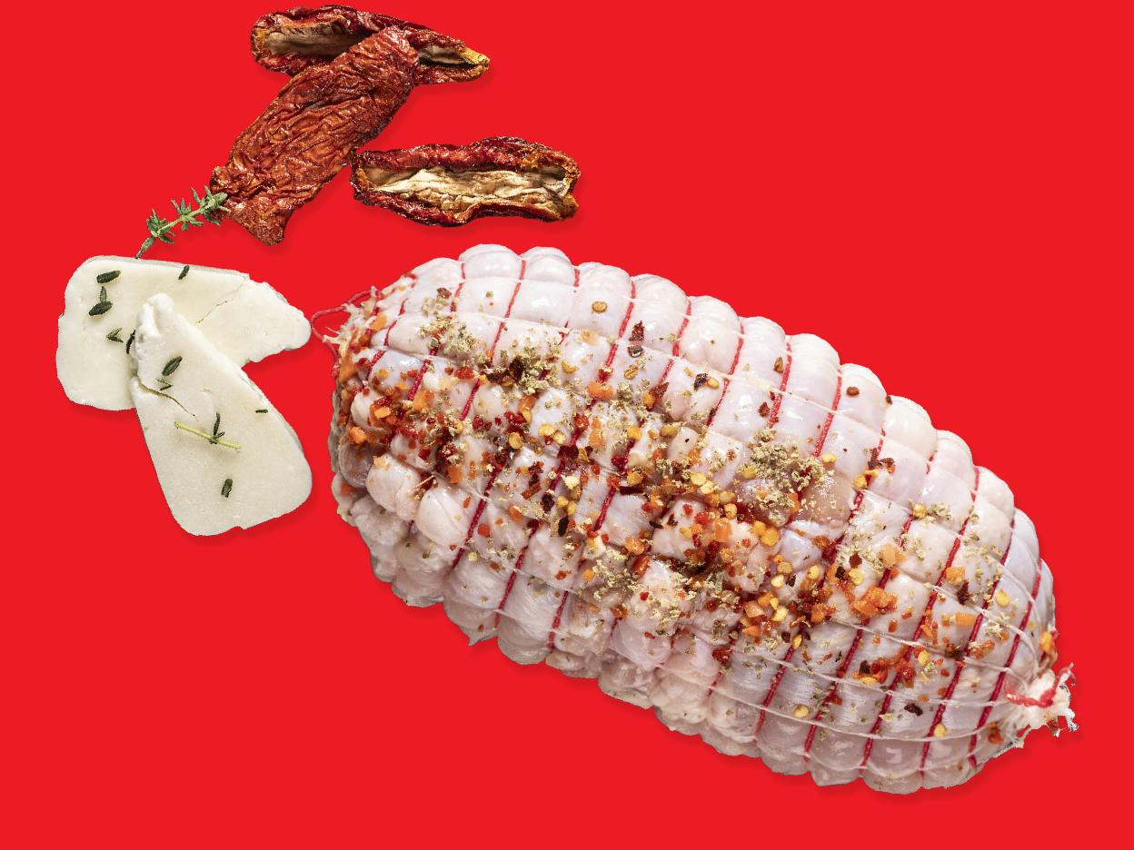 Herb-seasoned rolled meat, sun-dried tomatoes, and cheese on a red background.