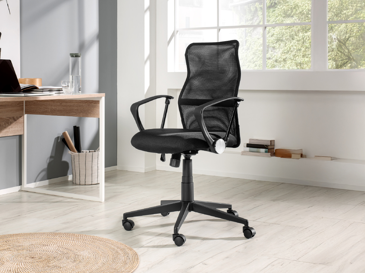 A black mesh office chair in a modern home office with a light wood desk.