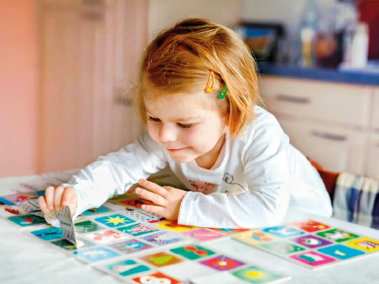 A young girl plays a board game with picture cards.