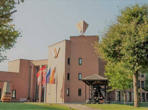 Brick building with a large 'Y' logo, flags, and trees.
