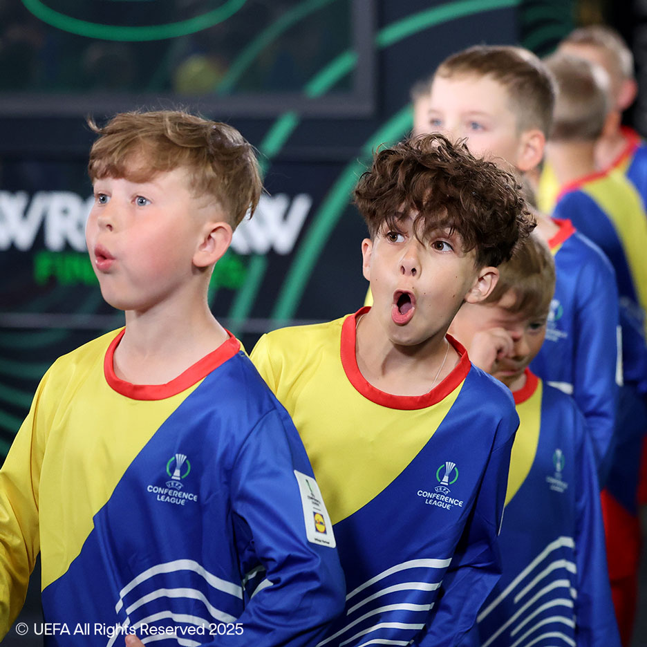 Two boys in yellow and blue shirts with football motifs, looking surprised.