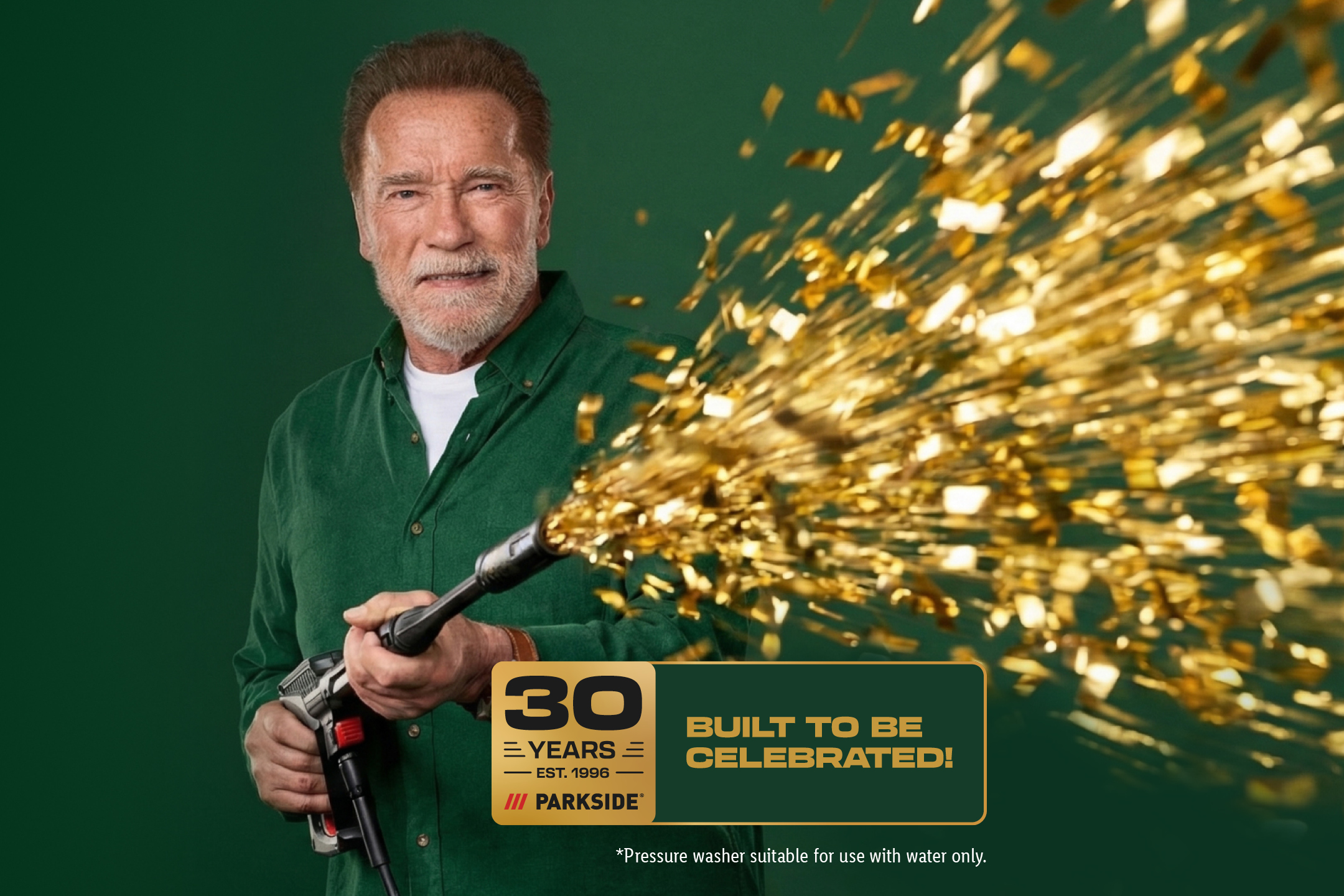 A man holding a pressure washer that sprays golden confetti, celebrating 30 years of tools.