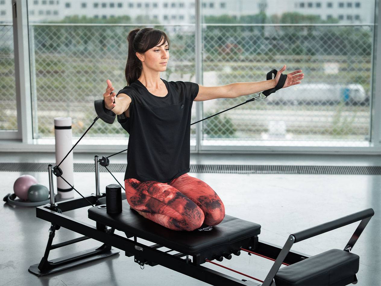 Woman doing Pilates on a reformer with resistance bands.