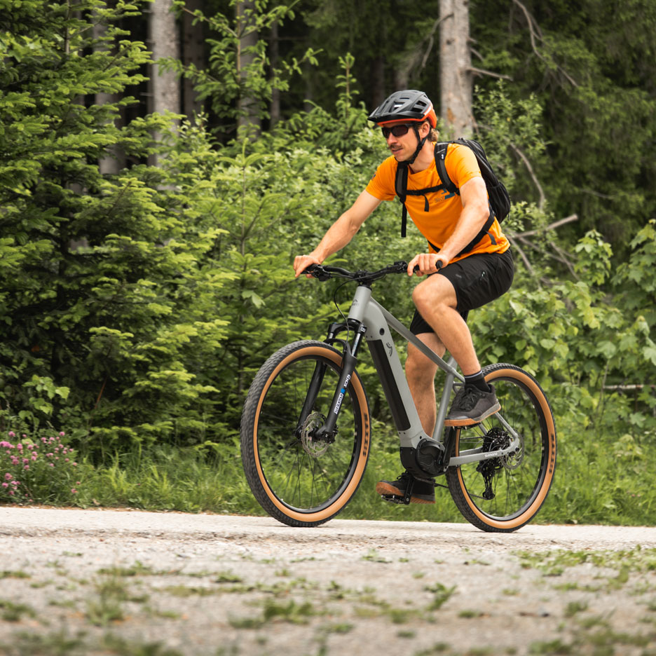 Man riding an e-bike on a forest trail.