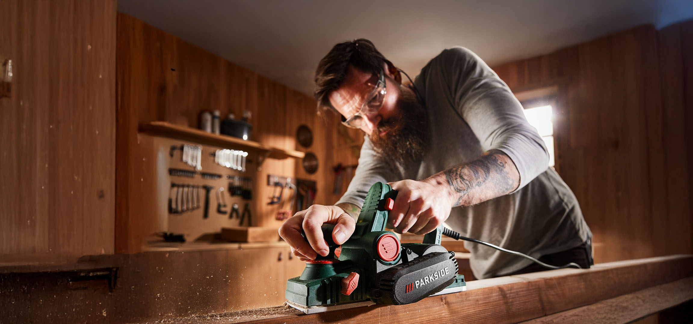 Man planing wood with a Parkside electric planer in a workshop.