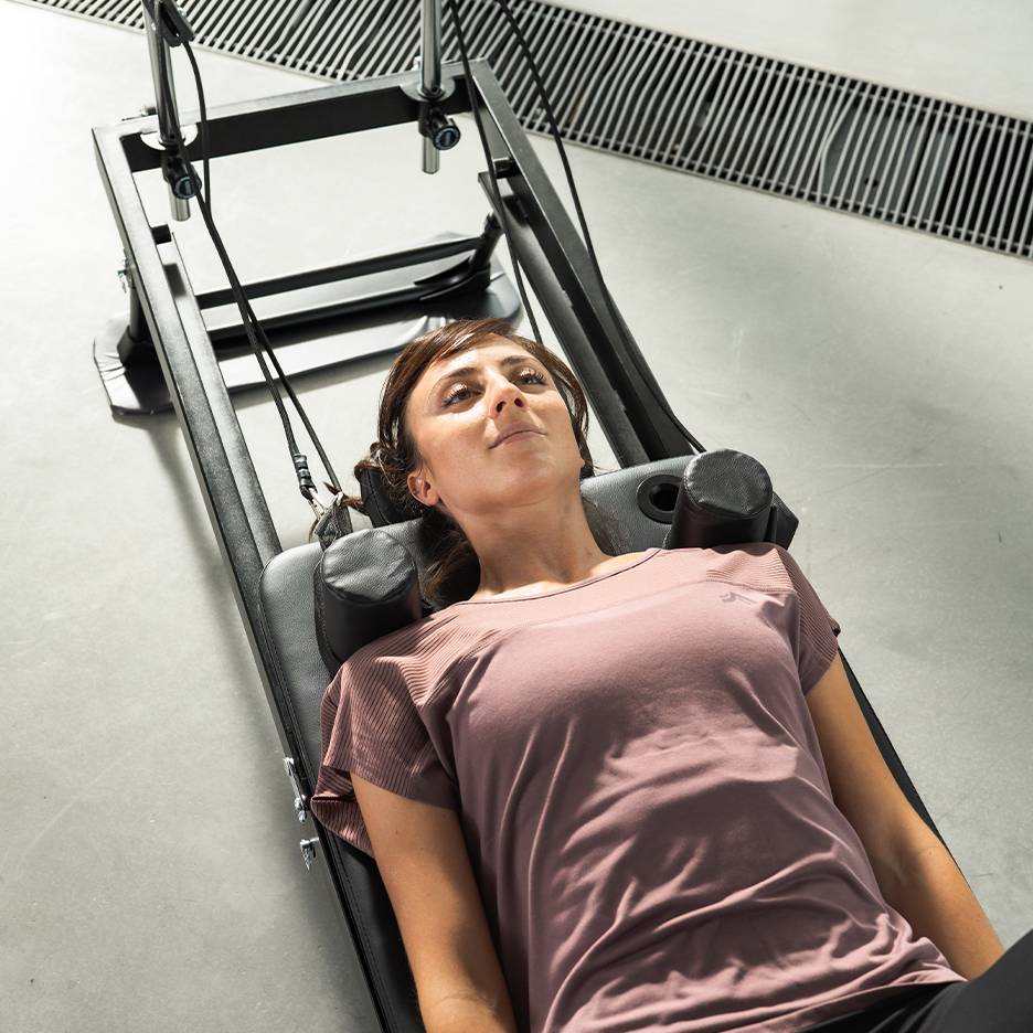 Woman lying on a fitness machine, looking upwards.