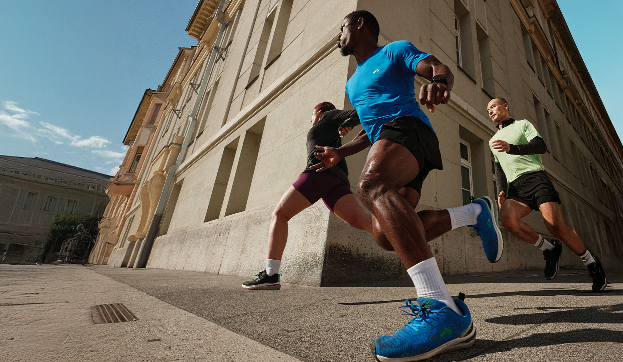 Three men running outdoors in athletic wear, showcasing active lifestyle.