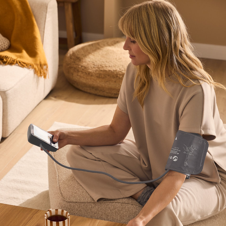 Woman measuring blood pressure at home with a digital blood pressure monitor.