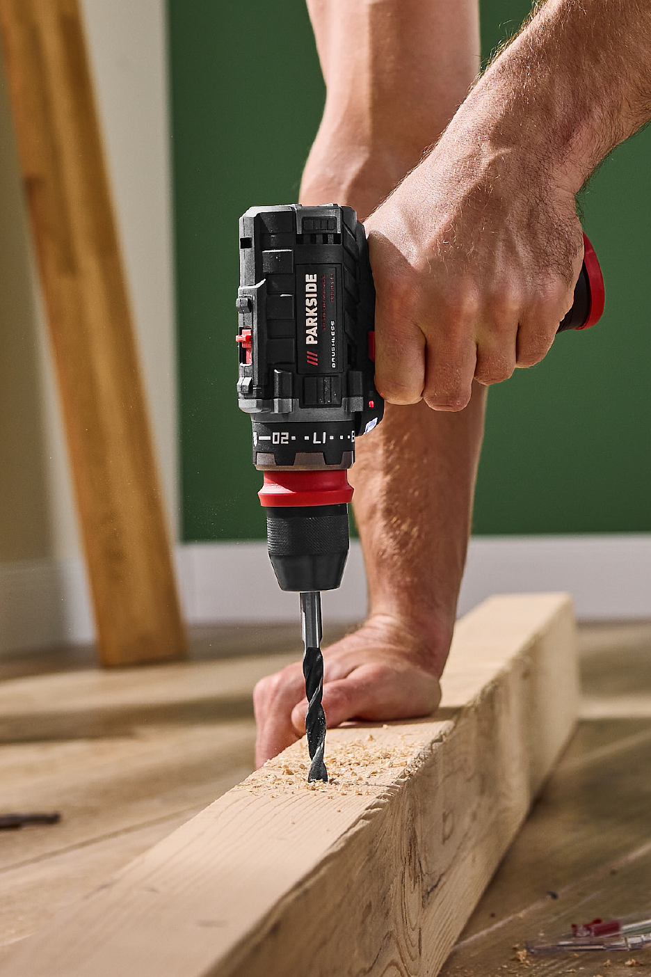 Άτομο τρυπάει ξύλο με ένα ασύρματο δράπανο Parkside.
