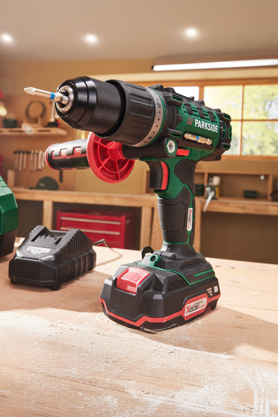 Ασύρματο δράπανο Parkside με μπαταρία και φορτιστή σε σκονισμένο πάγκο εργασίας.