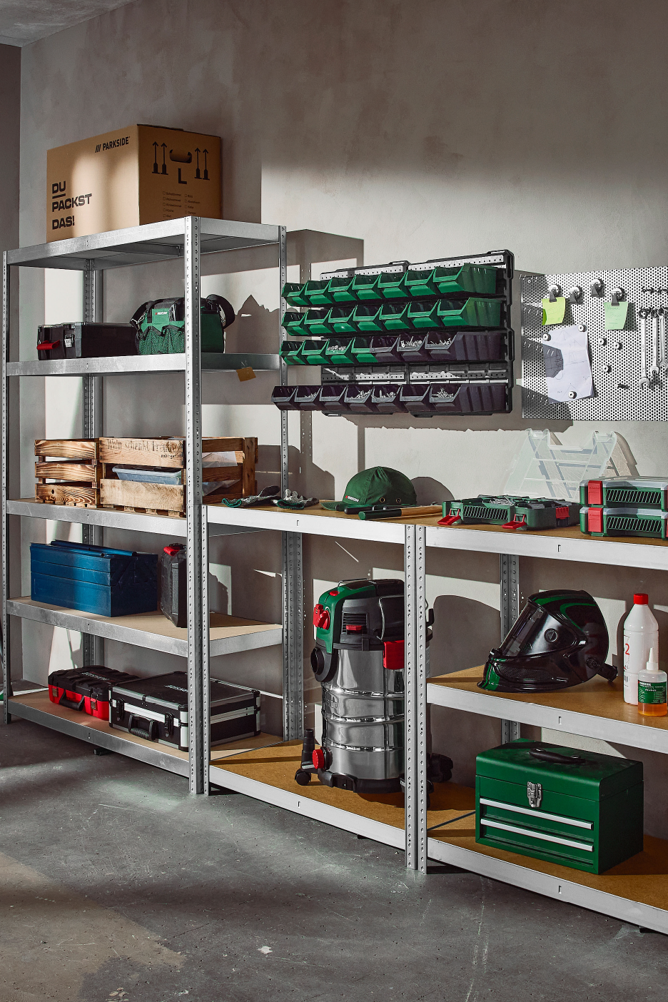 A well-organized garage or workshop with metal shelving, tools, storage boxes, and a vacuum.