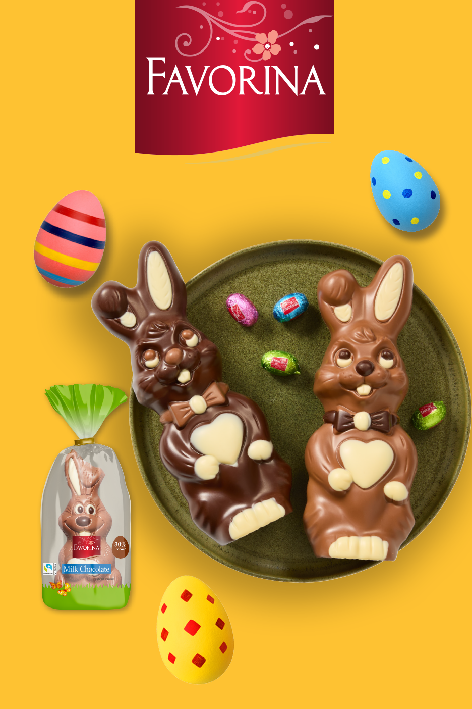 Δύο σοκολατένια πασχαλινά κουνελάκια σε πιάτο, με ένα συσκευασμένο κουνελάκι και διακοσμημένα αυγά.