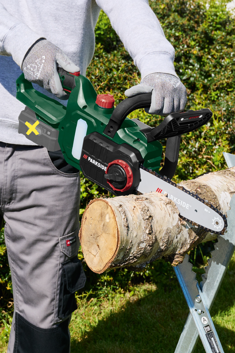 Άτομο κόβει ένα κορμό με ένα ασύρματο αλυσοπρίονο σε έναν πάγκο κοπής.