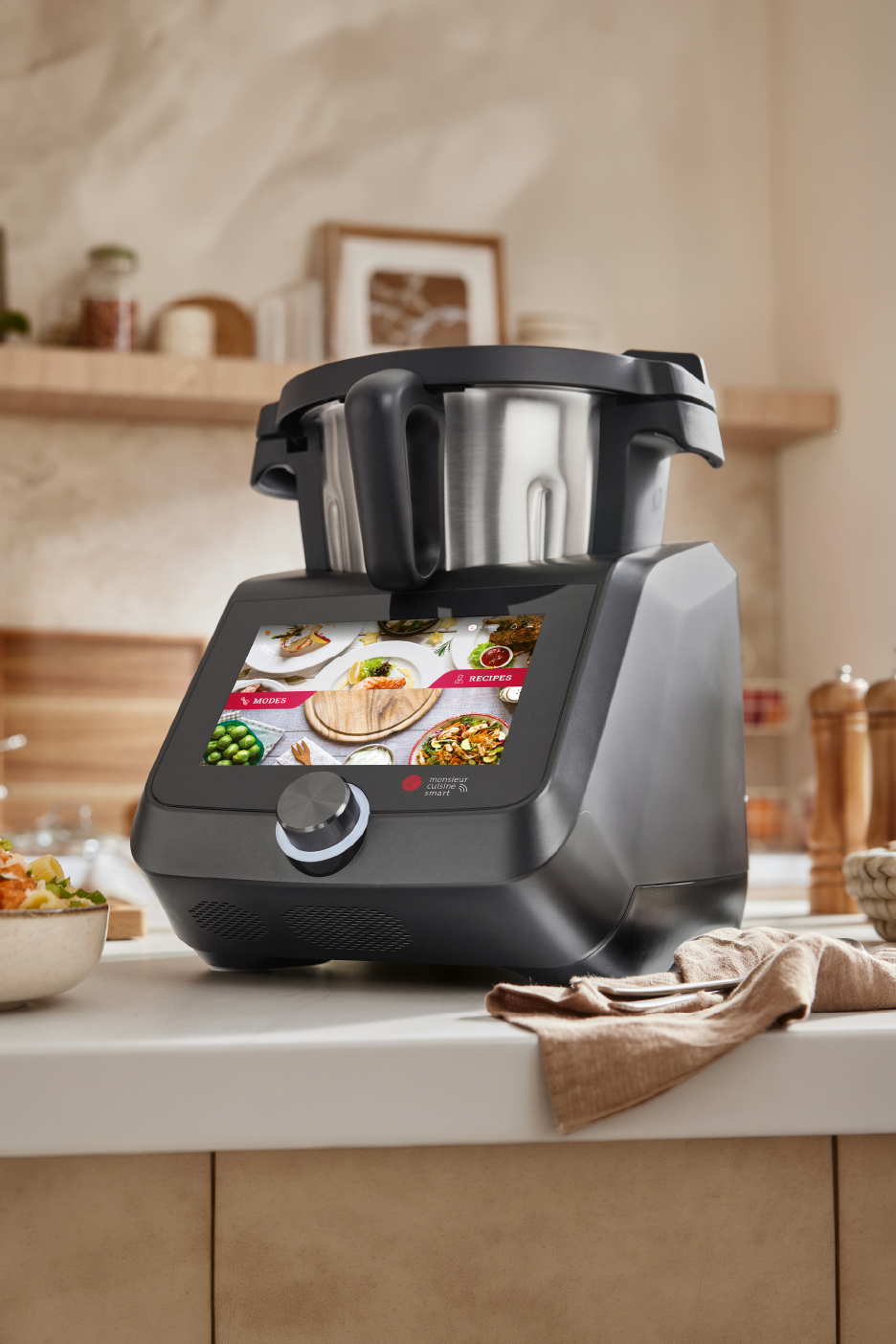 Έξυπνη συσκευή κουζίνας με μεγάλη οθόνη που εμφανίζει συνταγές, πάνω σε πάγκο κουζίνας.