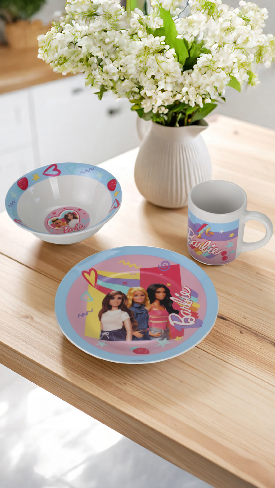 Barbie-themed children's dinnerware set with a bowl, plate, and mug on a wooden table.