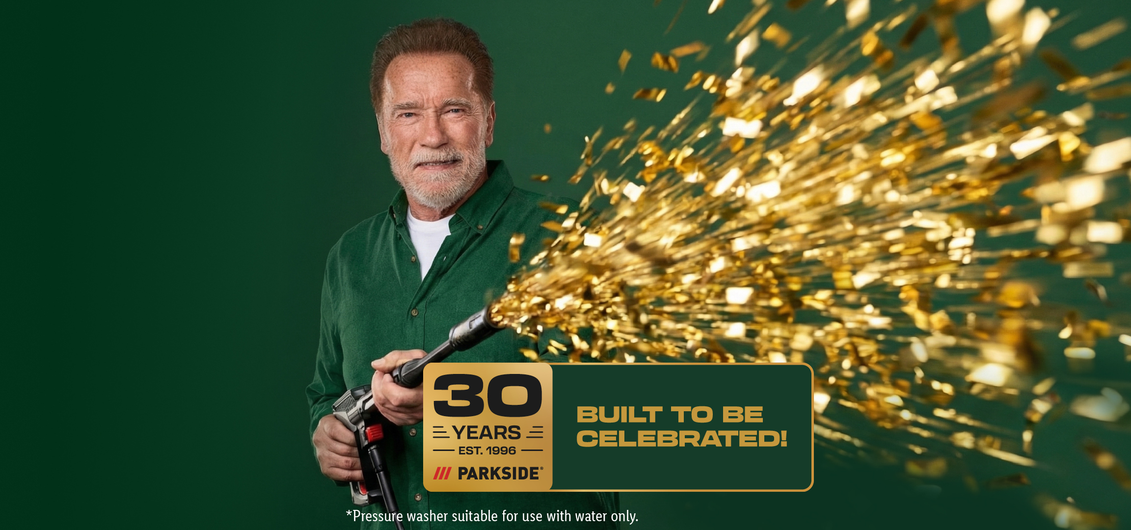 Man holding a pressure washer spraying golden confetti, celebrating 30 years.