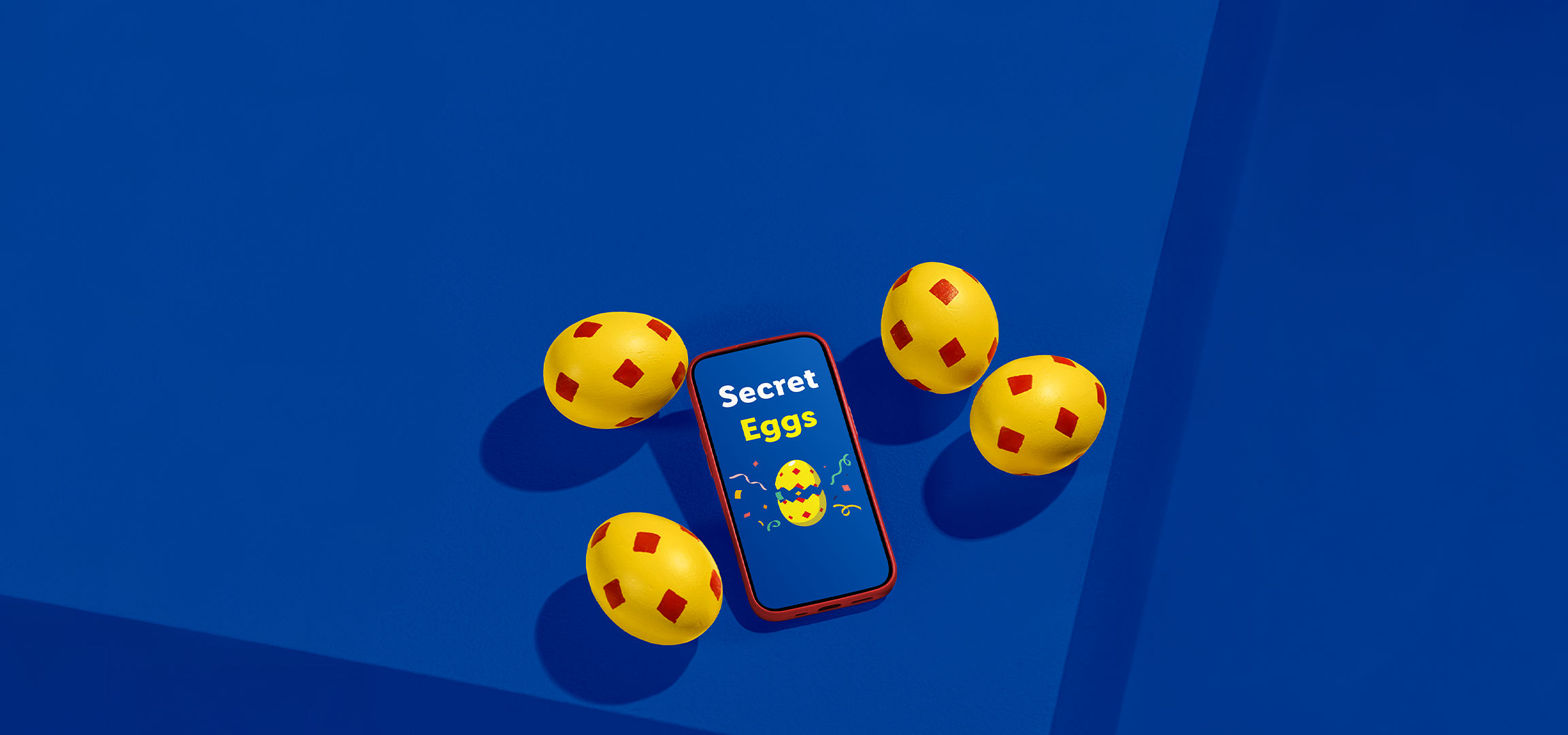 Κίτρινα αυγά με κόκκινα σχέδια και ένα smartphone που εμφανίζει 'Secret Eggs' σε μπλε φόντο.