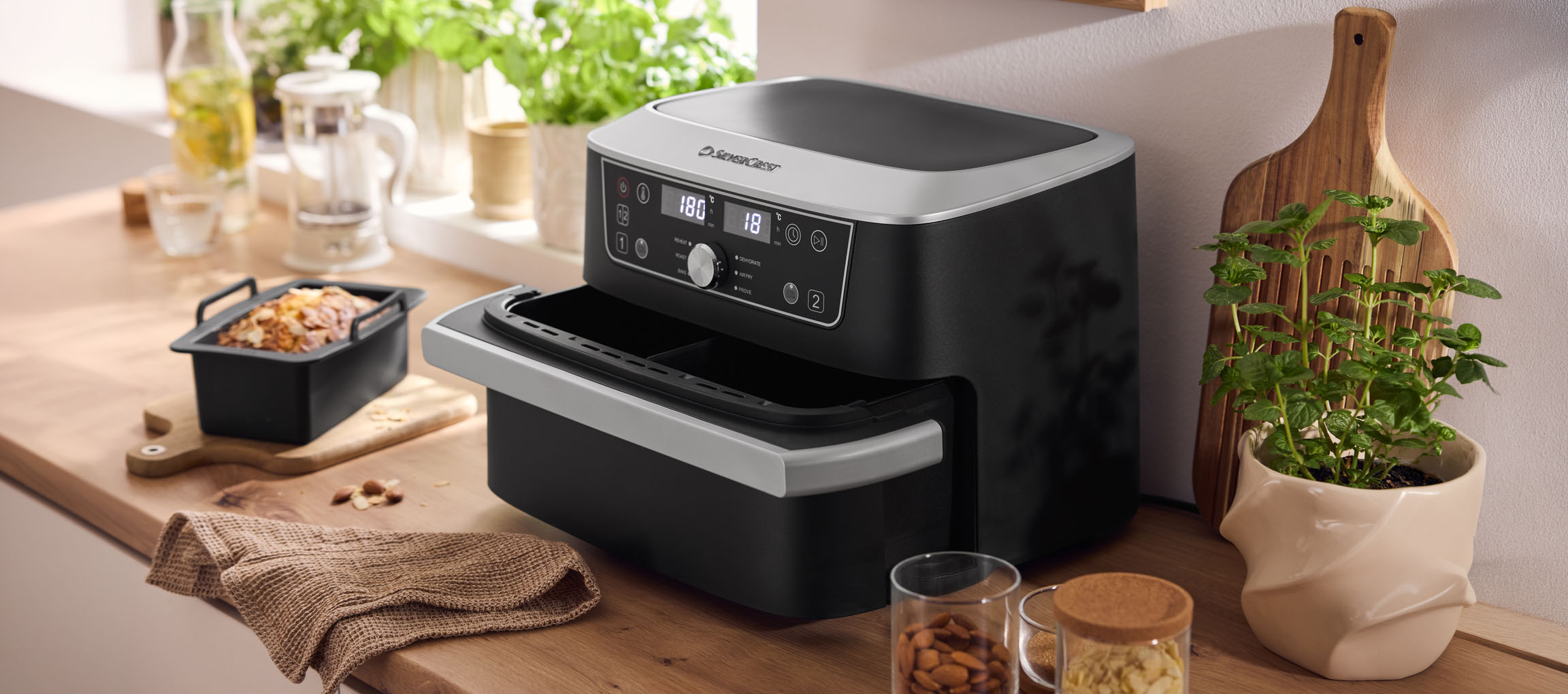 Μαύρη φριτέζα αέρος με διπλό φούρνο και ψημένο προϊόν σε ξύλινο πάγκο.