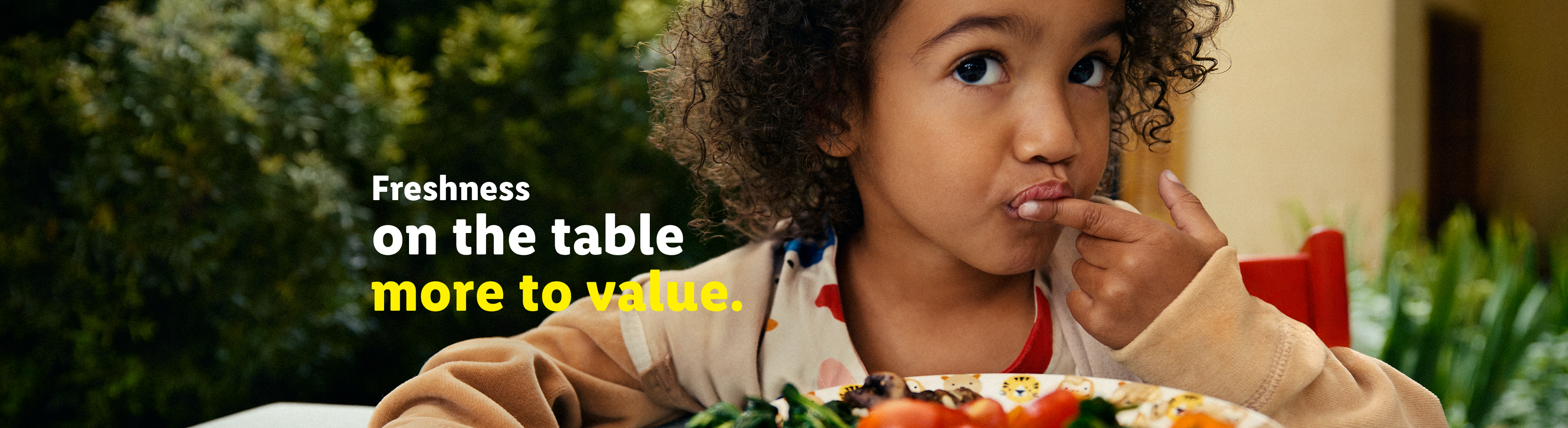 A child eating fresh food from a plate, with text: 'Freshness on the table, more to value.'