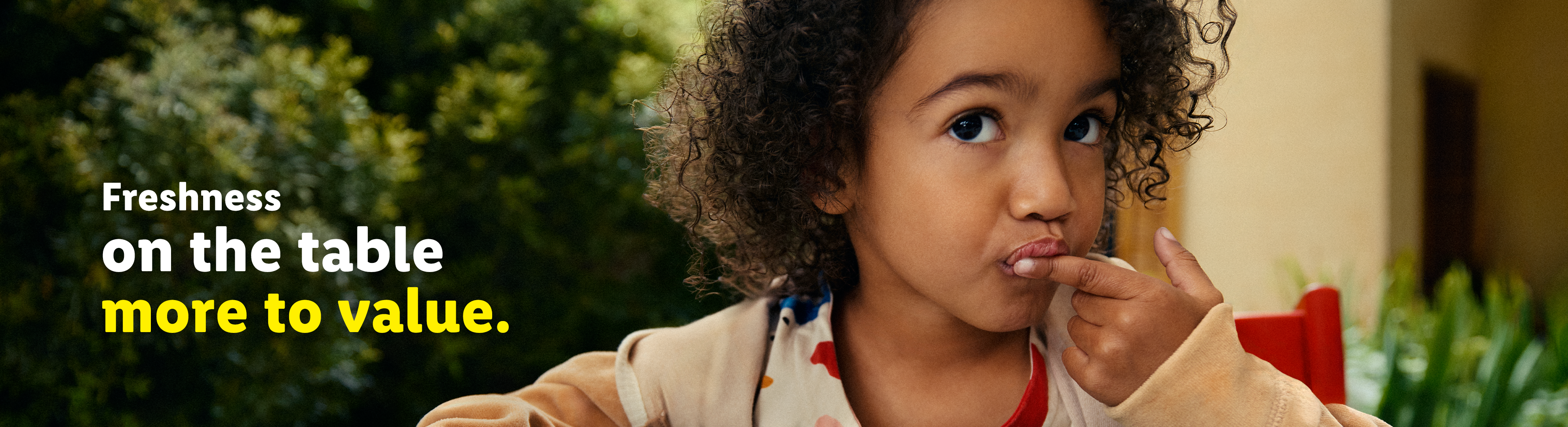 A young child with curly hair, making a funny face and touching their lips, with text about freshness.