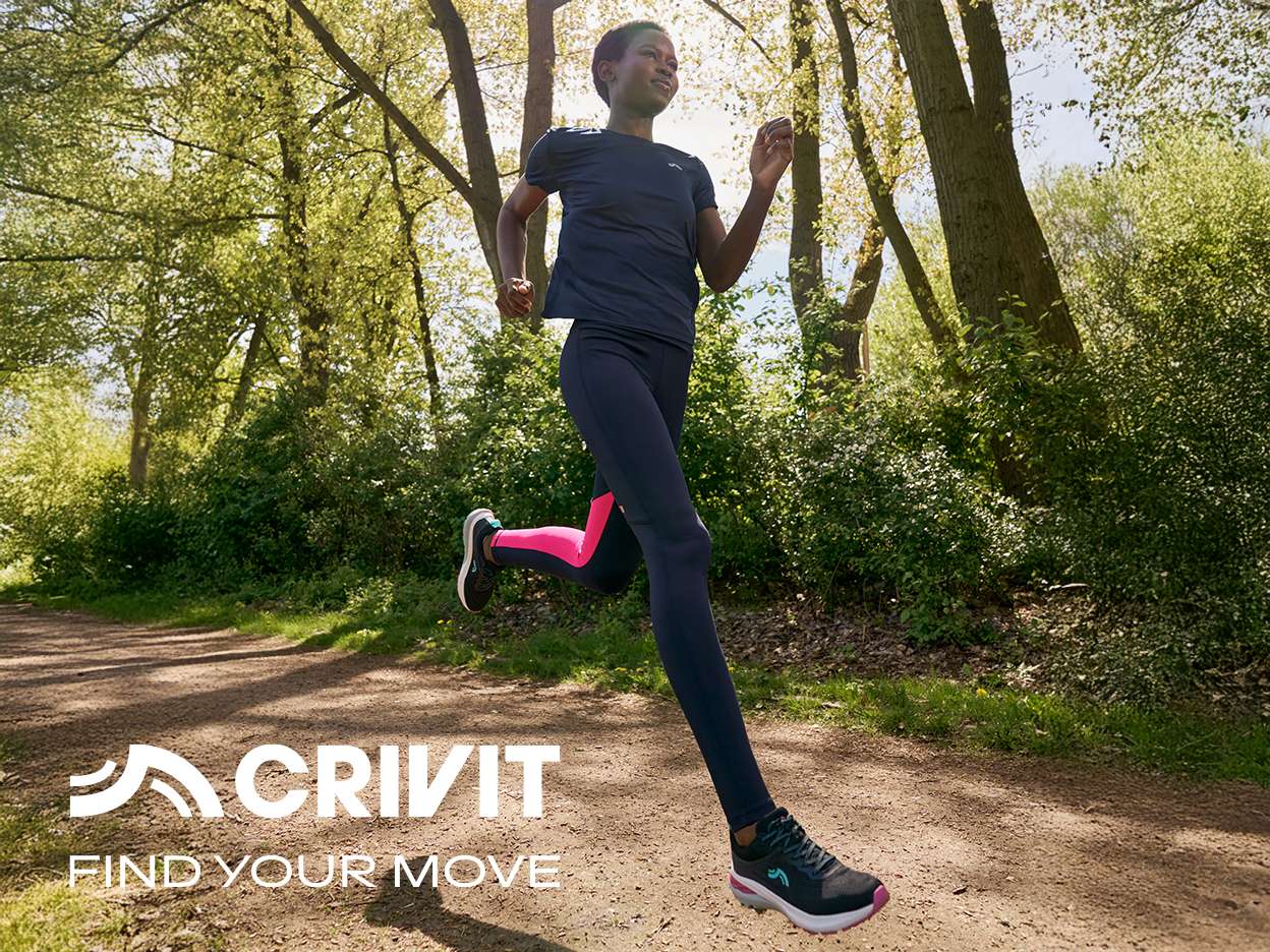 A person in Crivit activewear running on a dirt path through a forest.