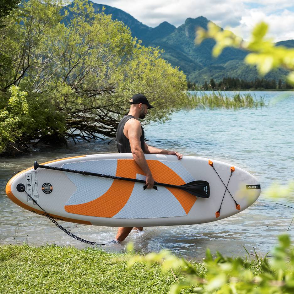 Man with CRIVIT paddleboard in water, ready to paddle.