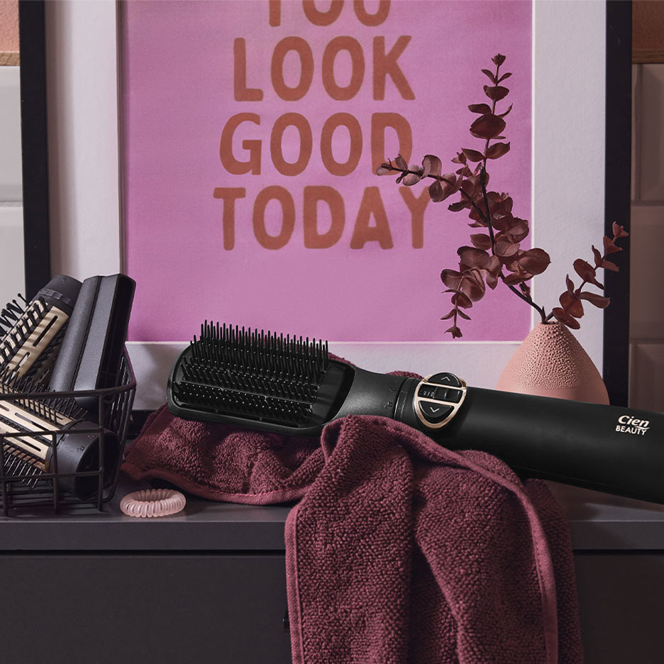 Cien Beauty hair straightening brush on a towel, with hair accessories and a poster.