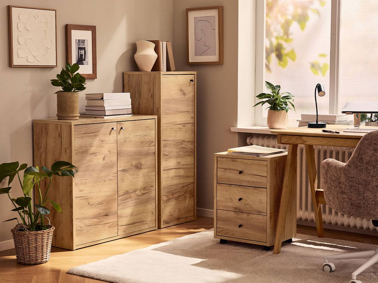 Ένα γραφείο στο σπίτι με ανοιχτόχρωμα ξύλινα ντουλάπια, καρέκλα γραφείου και λάμπα γραφείου.