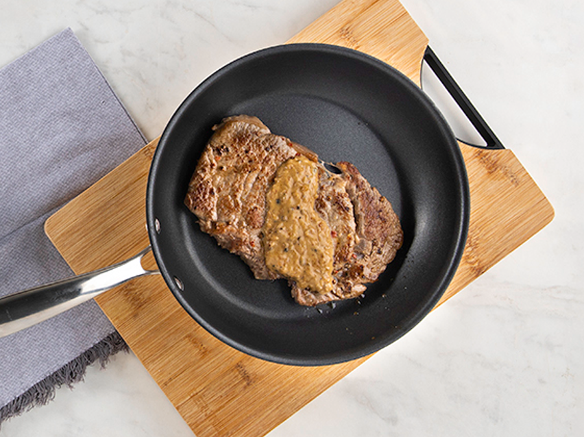 Steak with sauce in a pan.