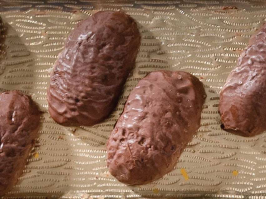 Σοκολατένια ψωμάκια αμυγδαλωτού σε χρυσό, ανάγλυφο δίσκο.