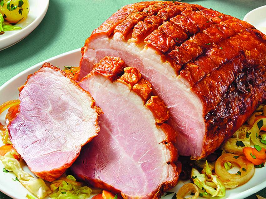 Sliced roasted pork belly with crispy crackling, served on a bed of vegetables.