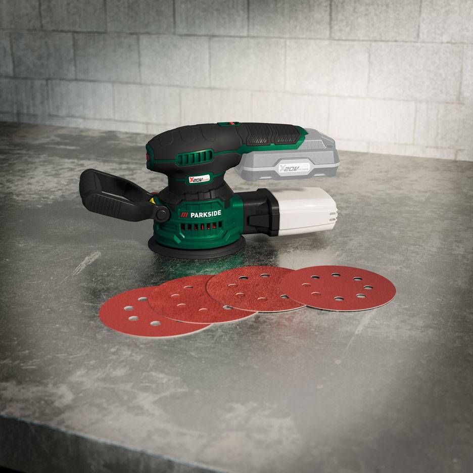 Cordless random orbital sander with battery and sanding discs on a metallic surface.
