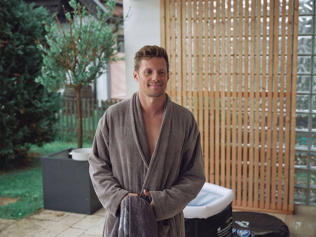 Man in a bathrobe with an inflatable hot tub in the background.