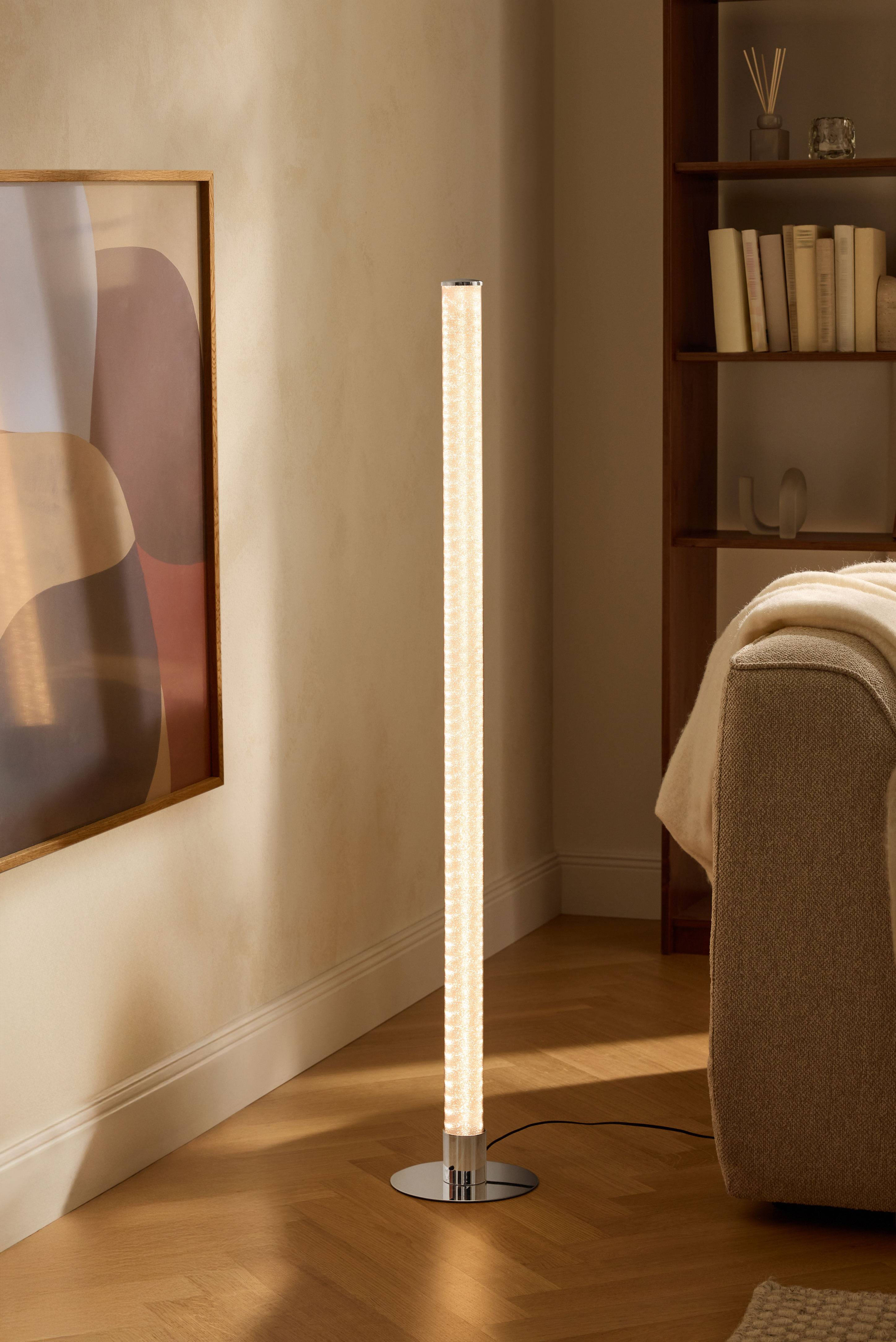 Modern floor lamp in living room with bookshelf and sofa.