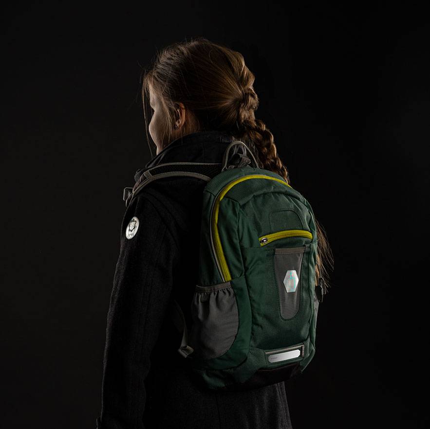 Woman with a green and gray backpack on her back, against a dark background.