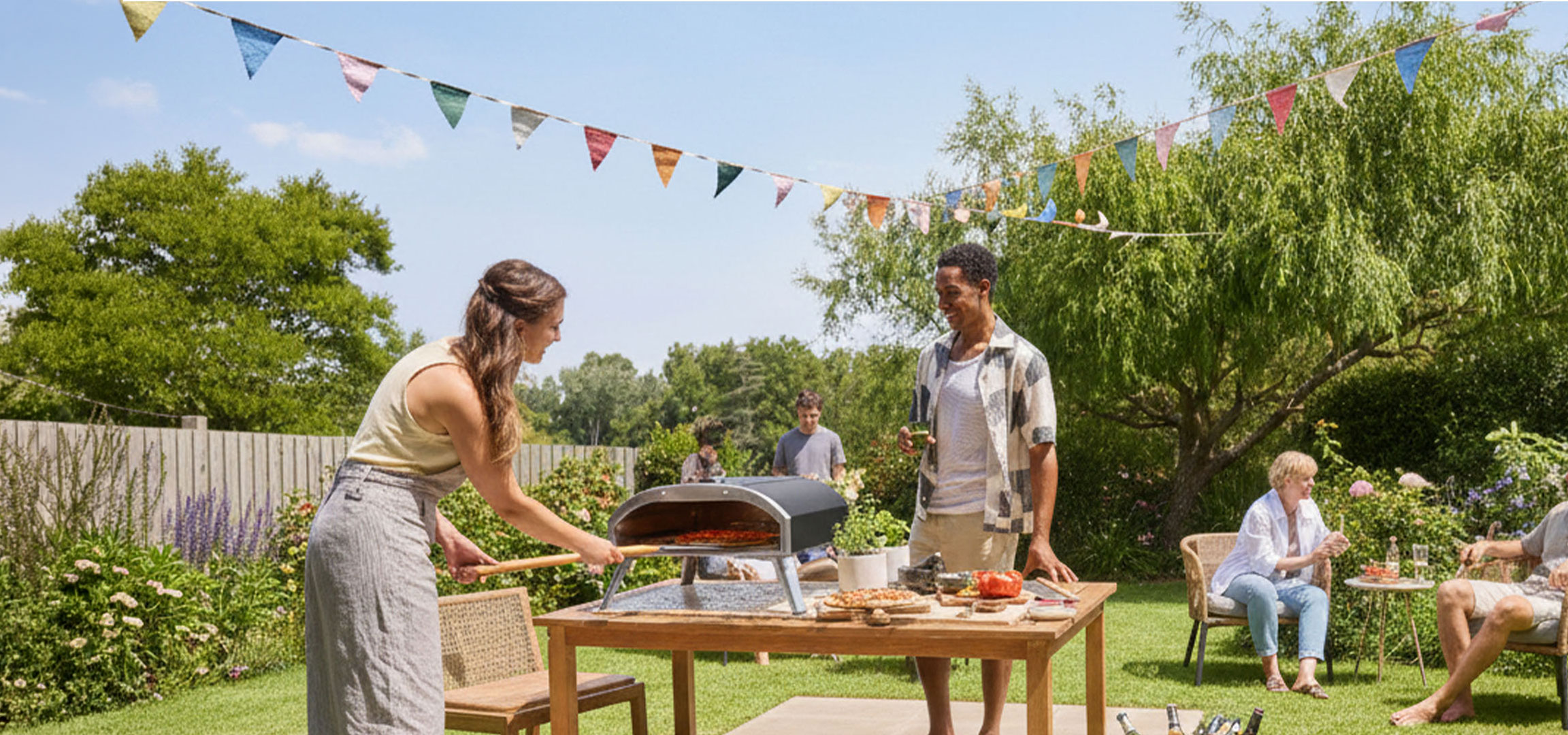 Group of friends making pizza in an outdoor oven, enjoying a summer day.