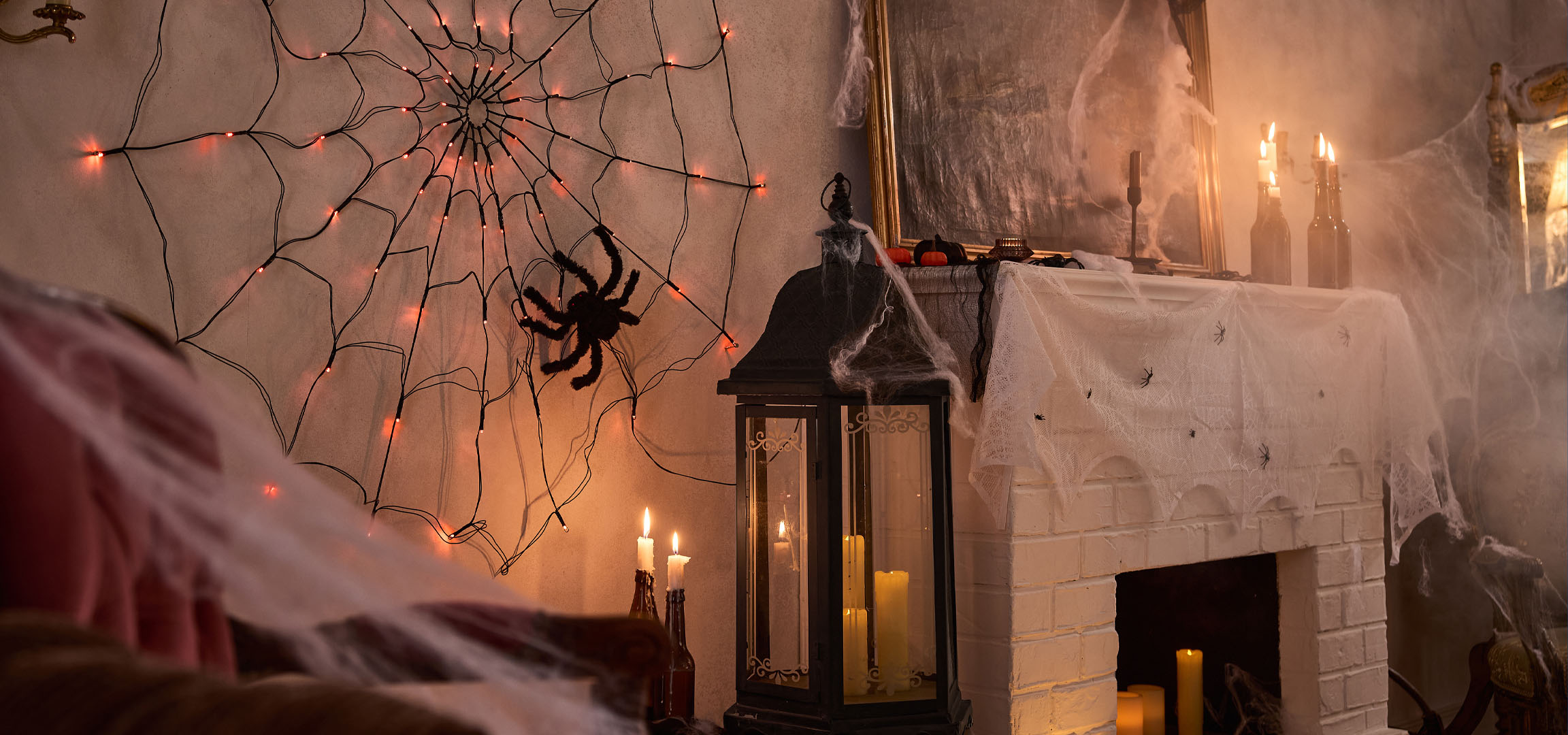 Halloween decorations with spiderweb lights, a large spider, and candles.