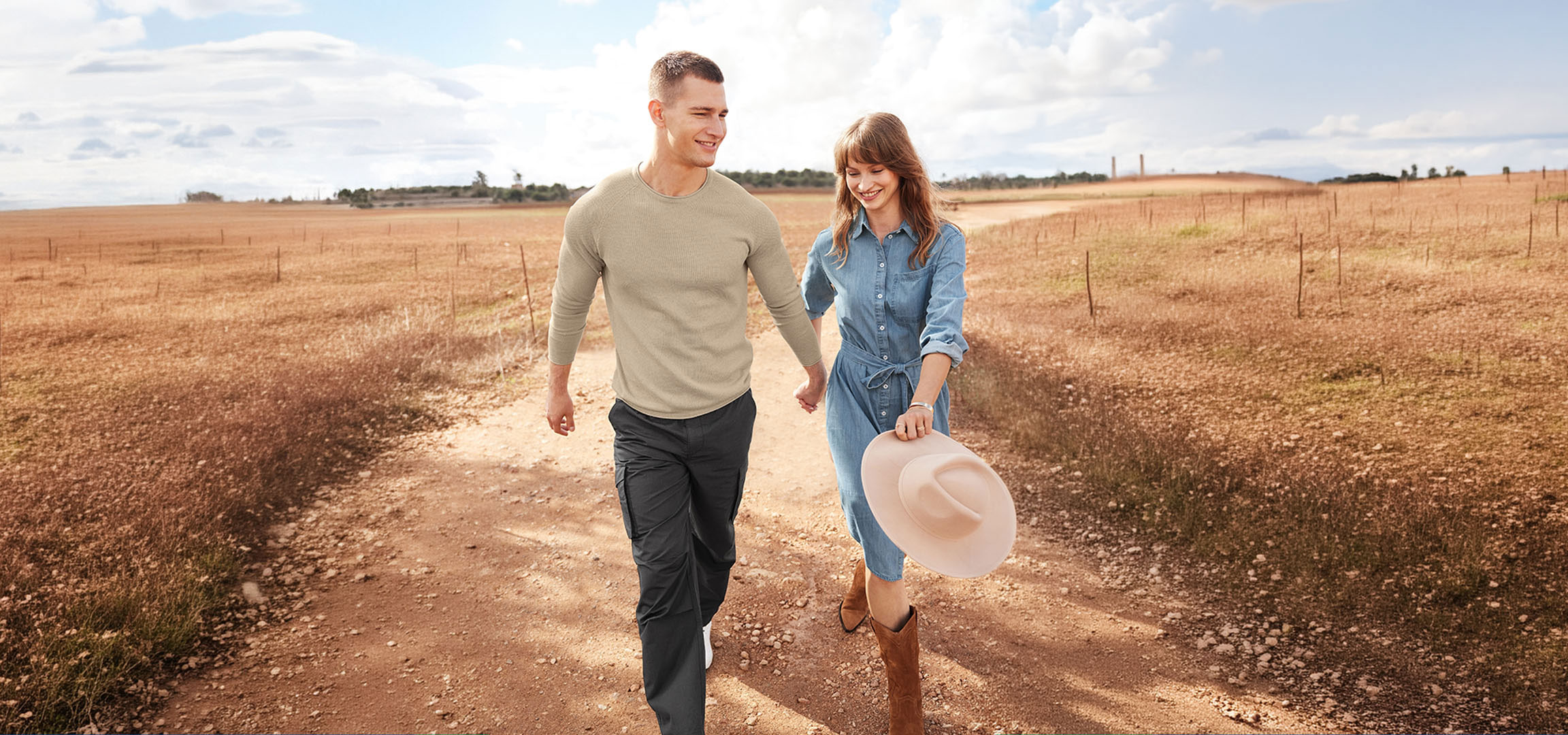 AI generated image: Couple in casual wear walking on a dirt road through a field.