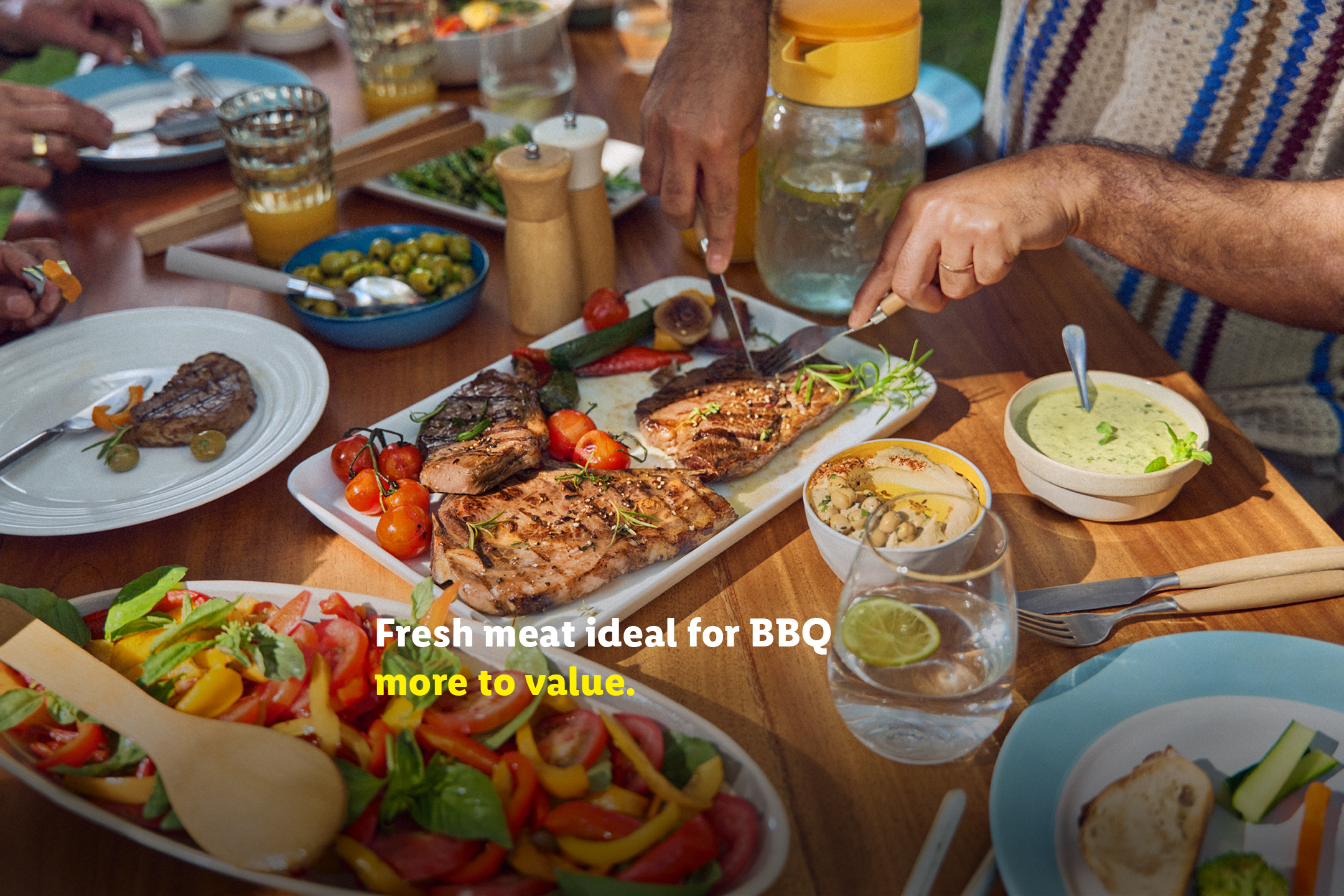 BBQ meat, grilled vegetables, and salads on a wooden table. Text: Fresh meat ideal for BBQ, more to value.