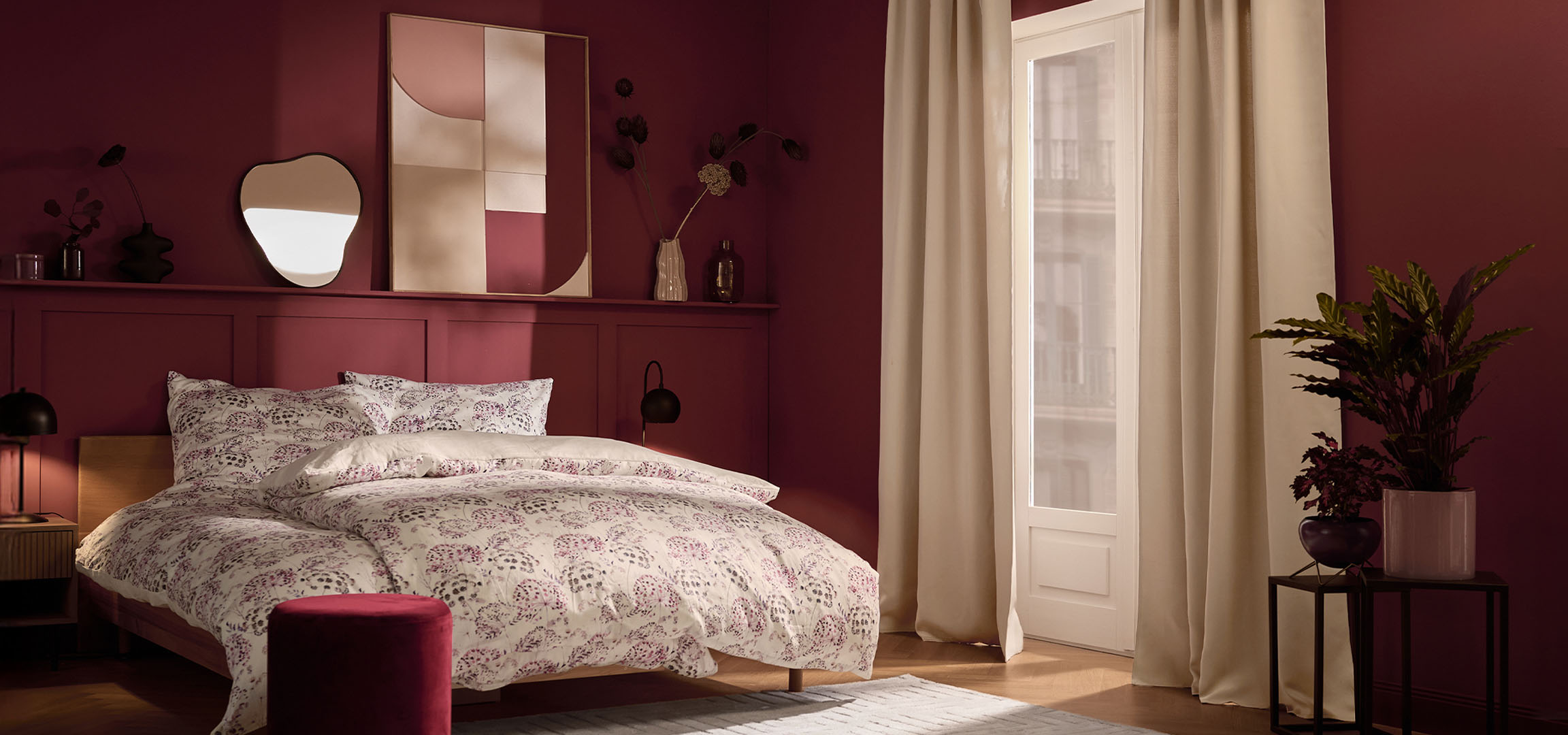 Bedroom with maroon walls, bed with white floral patterned bedding, and plants.